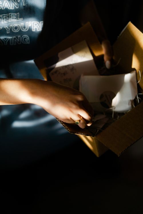 Free Close-up of a person unpacking a gift box, with sunlight casting shadows, creating a warm atmosphere. Stock Photo