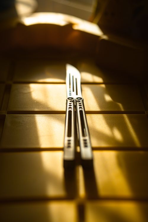 Free Artistic close-up of a metallic knife on a table with dramatic sunlight, perfect for design concepts. Stock Photo