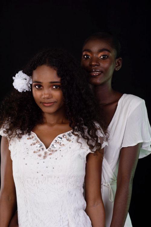 Free Two fashionable black women posing in a studio wearing elegant white outfits, showcasing beauty and style. Stock Photo