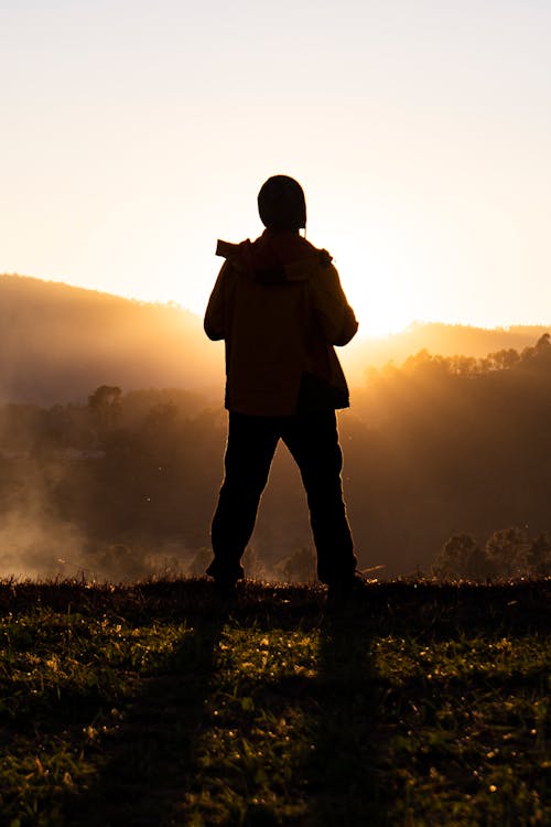 Free Silhouette of Man Standing on Grass Field during Sunset Stock Photo