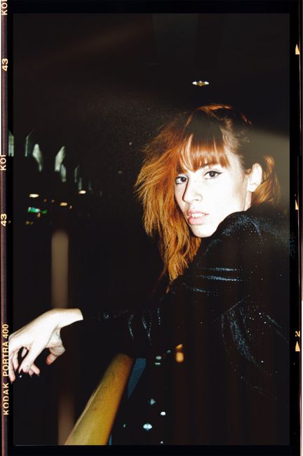 Portrait of a fashionable woman posing stylishly indoors in a sparkling black ensemble.
