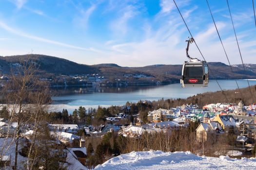 Scenic winter landscape of Mont-Tremblant with a gondola overlooking the snowy village and lake.