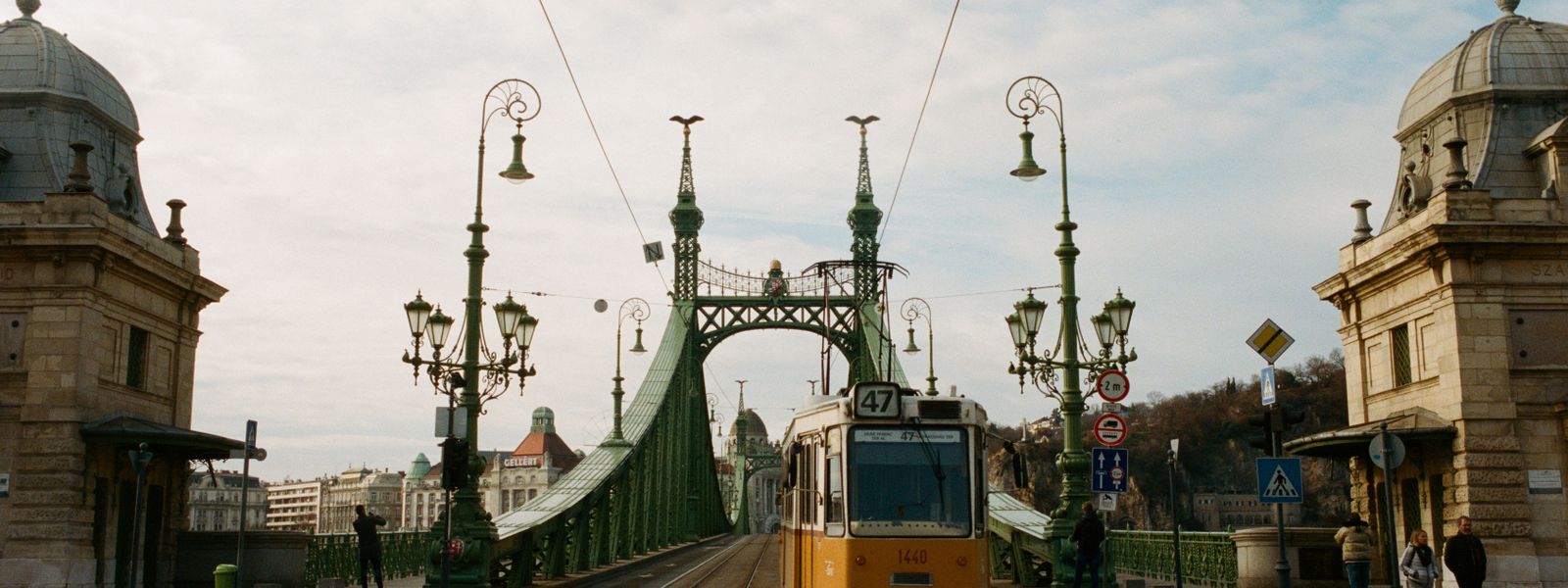 Tram crossing the iconic Liberty Bridge in Budapest, showcasing historical architecture and urban atmosphere.
