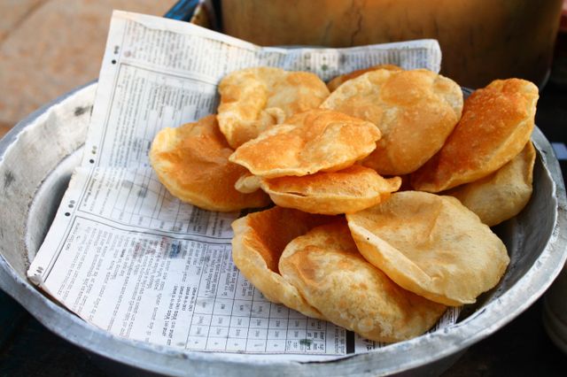 Crispy homemade fried bread served on newspaper, perfect for breakfast or snacks.