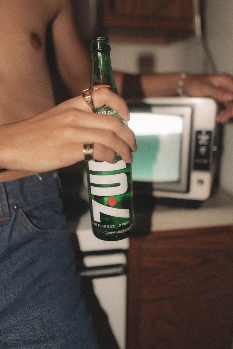 Hand Wearing Ring Holding Glass Bottle Of Soda