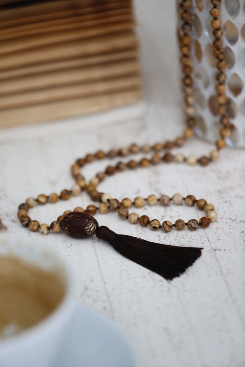 Free Artistic close-up of a handmade wooden bead necklace with a tassel on a table. Stock Photo