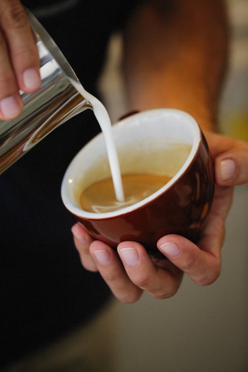 Pouring Milk into Coffee in Cup