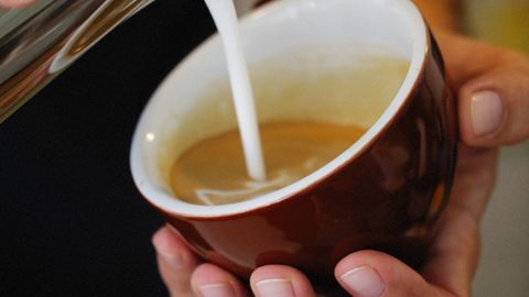 Detailed shot of milk being poured into espresso for perfect latte art creation.