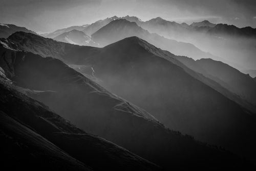 Free A dramatic black and white image of foggy mountains at dawn, capturing the serene beauty of the landscape. Stock Photo