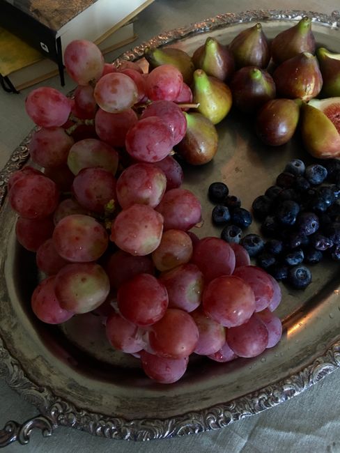 A close-up of fresh grapes, blueberries, and figs arranged beautifully on a silver tray.