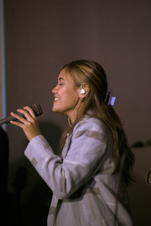 Free Asian woman in blazer performing live with a microphone indoors. Stock Photo