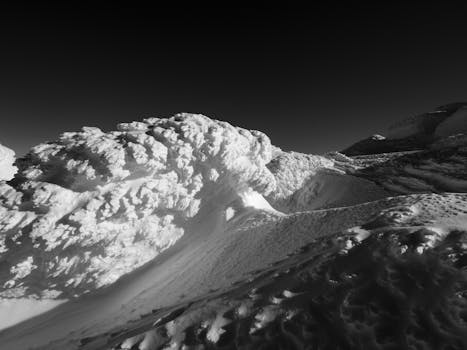 Stunning black and white photo capturing snow-covered mountain terrain under a clear sky.