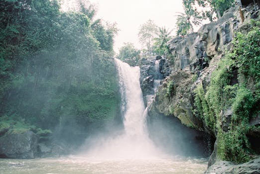 Beautiful waterfall cascading down rocky cliffs surrounded by lush greenery in Bali, Indonesia.