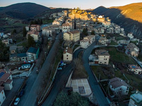 Stunning aerial view of a charming Italian hilltop town at sunrise, showcasing the picturesque architecture and surrounding hills.