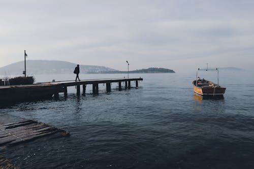 Silhouette of Person Walking on Wooden Dock 
