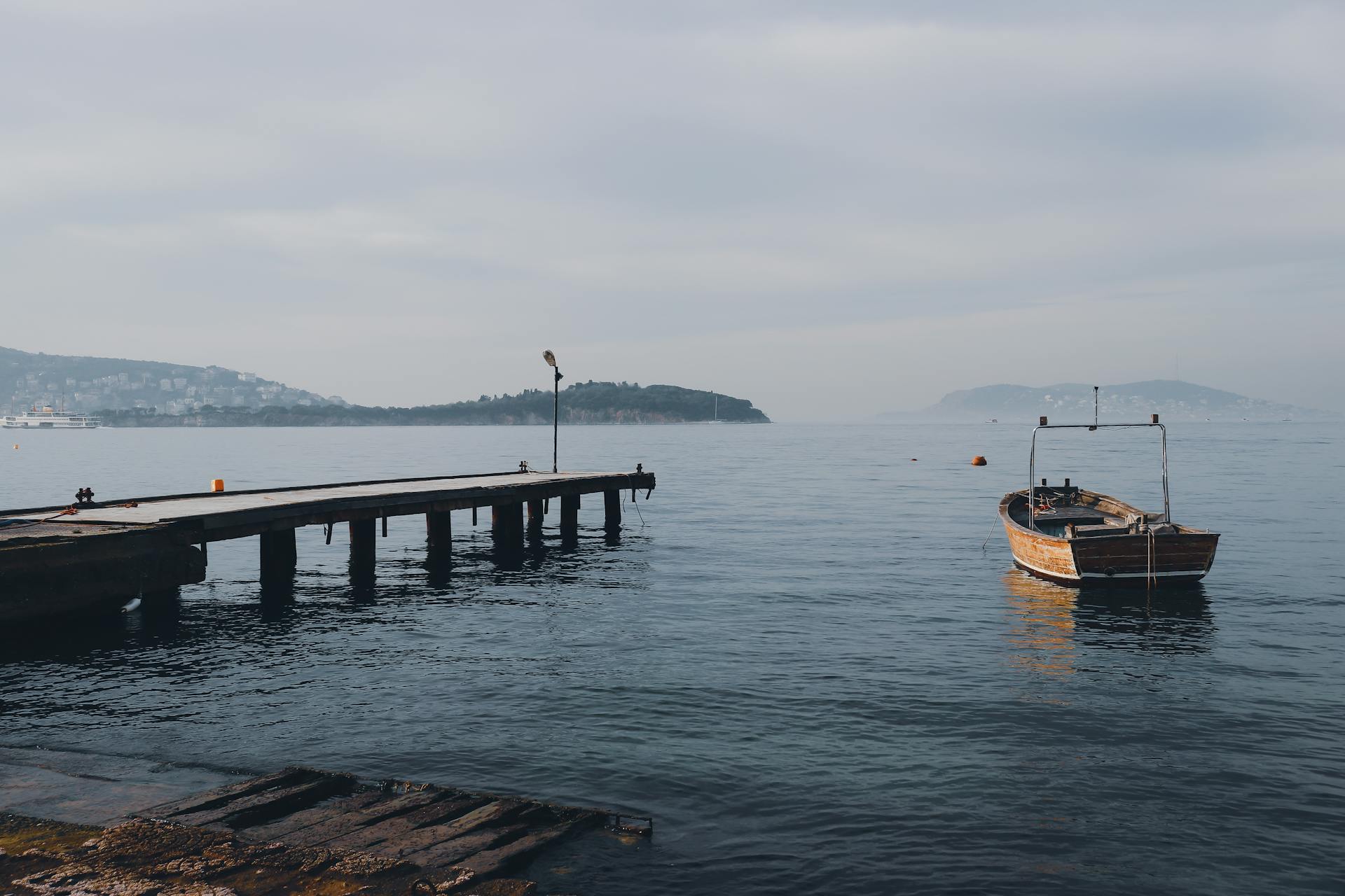 A serene scene of a weathered wooden boat docked by an old jetty on a calm sea.
