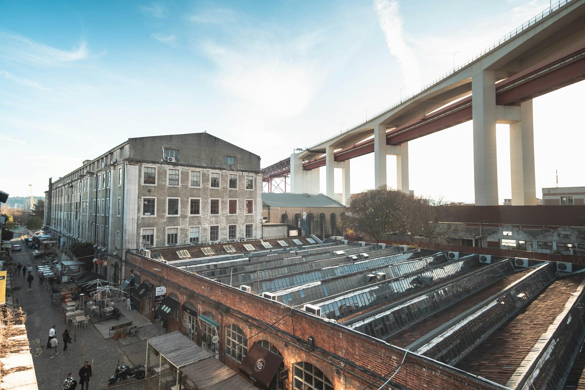 Aerial view of Lisbon's LX Factory with iconic bridge in the background.