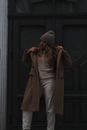 Woman in Brown Coat Standing Near Black Wooden Door