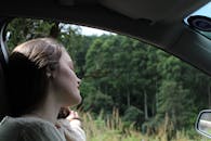 一名年轻女子在宁静的公路上放松，享受着被郁郁葱葱的绿色植物包围的旅途