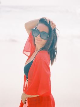 Stylish woman in sunglasses and bikini posing confidently on a sunny Bali beach.