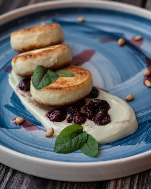 Free Close-up of ricotta pancakes garnished with berries and greens on a stylish ceramic plate. Stock Photo