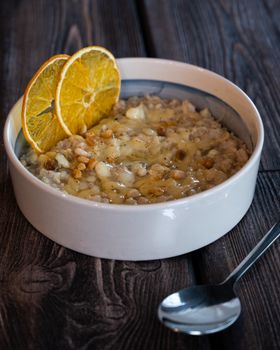 Delicious barley porridge with orange slices served in a rustic style bowl.