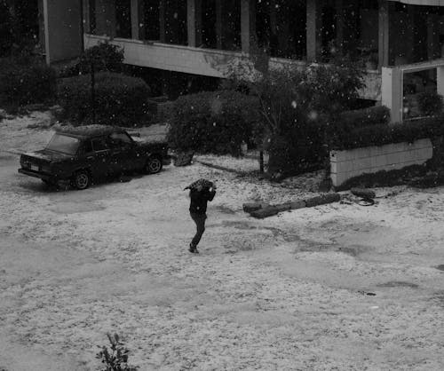 Grayscale Photo of Person running on Snow Covered Ground 