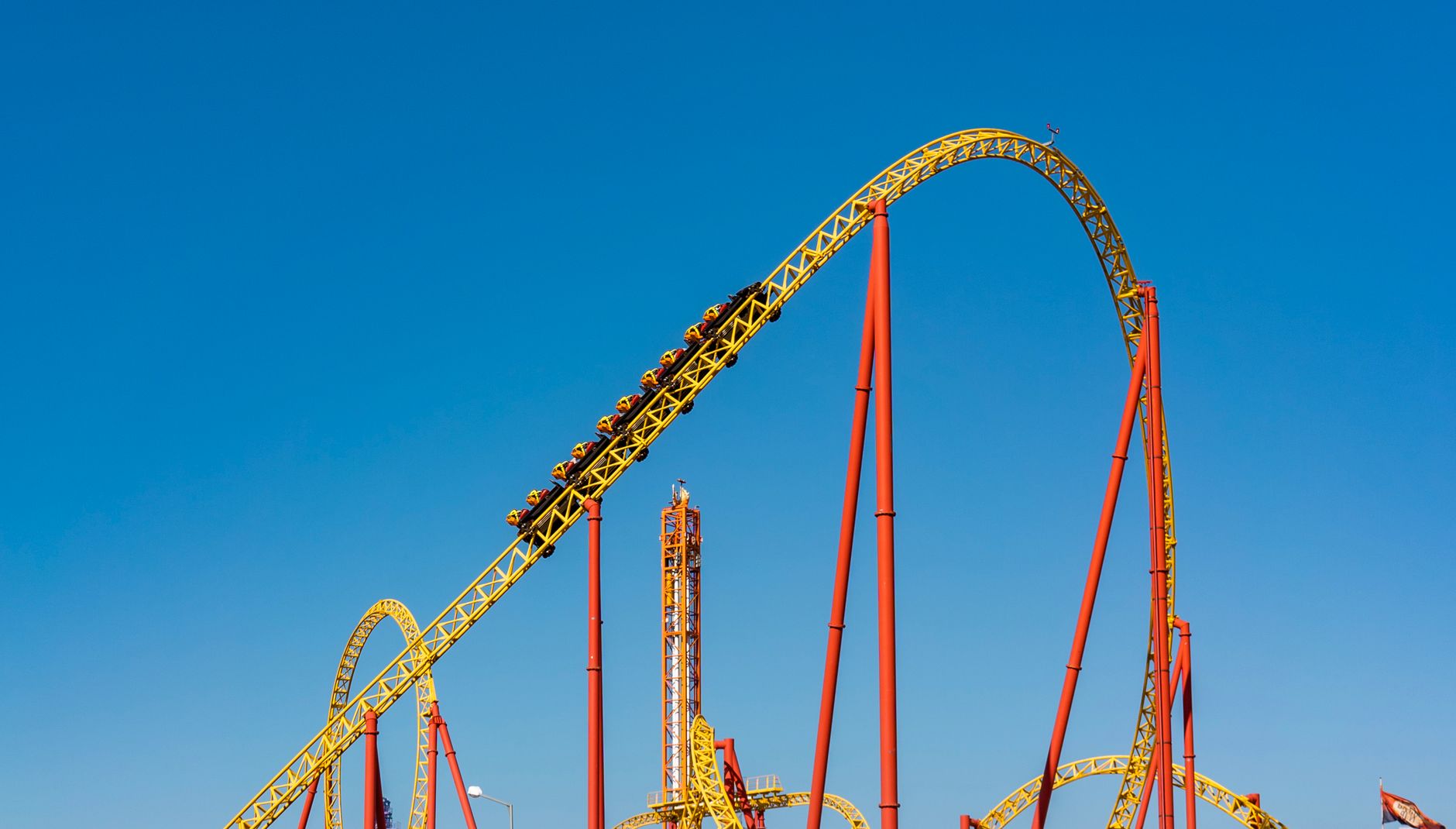 An exhilarating view of a roller coaster at an amusement park against a clear blue sky.
