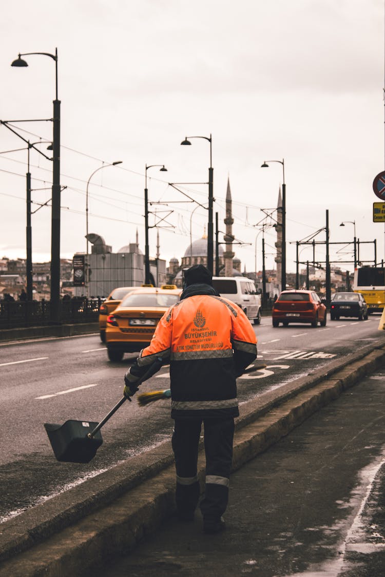 A Person Sweeping A Dirt On The Road