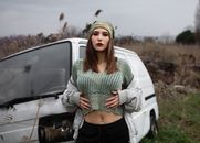 Woman in Green Blouse Standing Beside a Mini Van