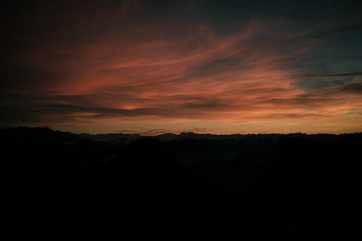 A breathtaking sunset silhouette of the mountains with dramatic clouds in Deutschland.