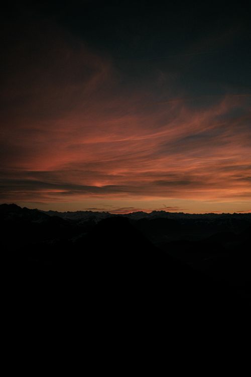 Free A breathtaking view of mountains silhouetted against a vibrant sunset sky in Germany. Stock Photo