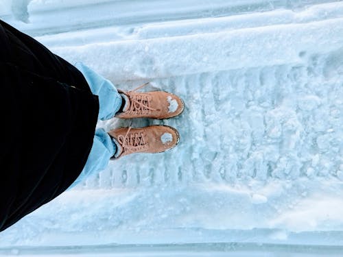 Person Wearing a Brown Hiking Shoes Standing on Snow