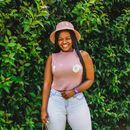Woman in Gray Tank Top and White Pants Standing Beside Green Plants