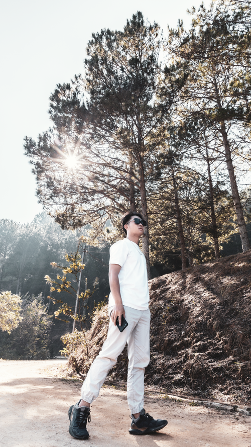 Free Fashionable man walking under sunlight in Da Lat forest, Vietnam. Stock Photo