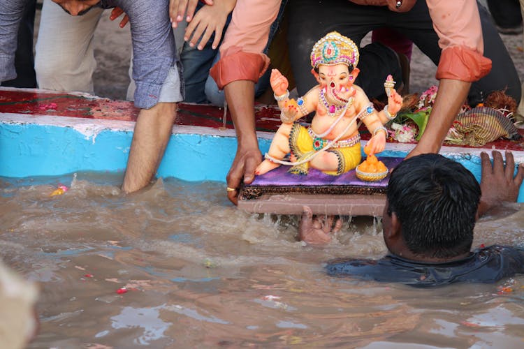 People Lowering Statue Of Hindu God Into Murky Water