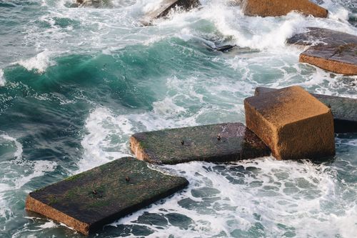 Free Concrete breakwaters with waves crashing, emphasizing nature's power against man-made structures. Stock Photo