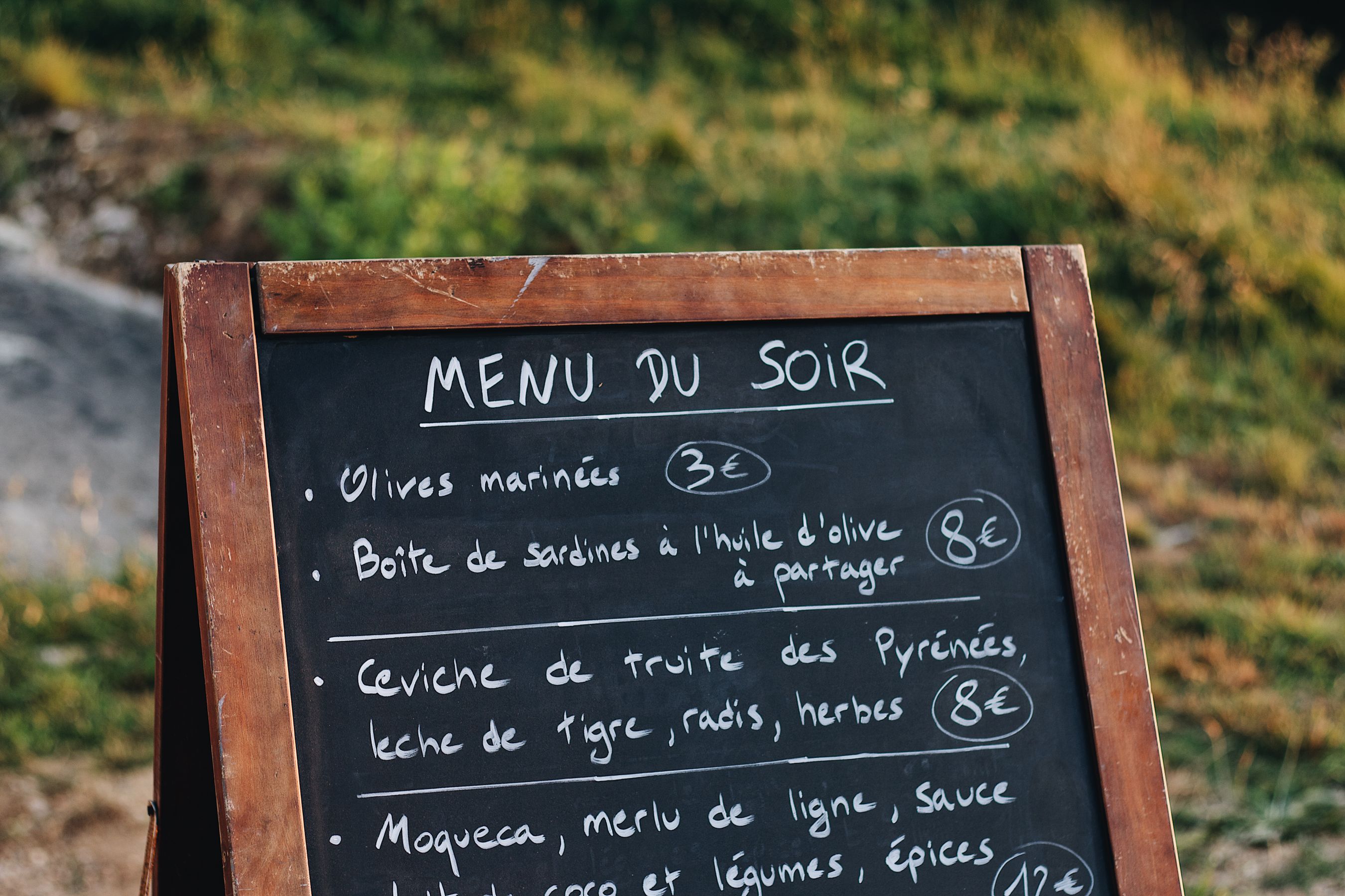 Chalkboard menu stand listing dishes and prices outside a restaurant