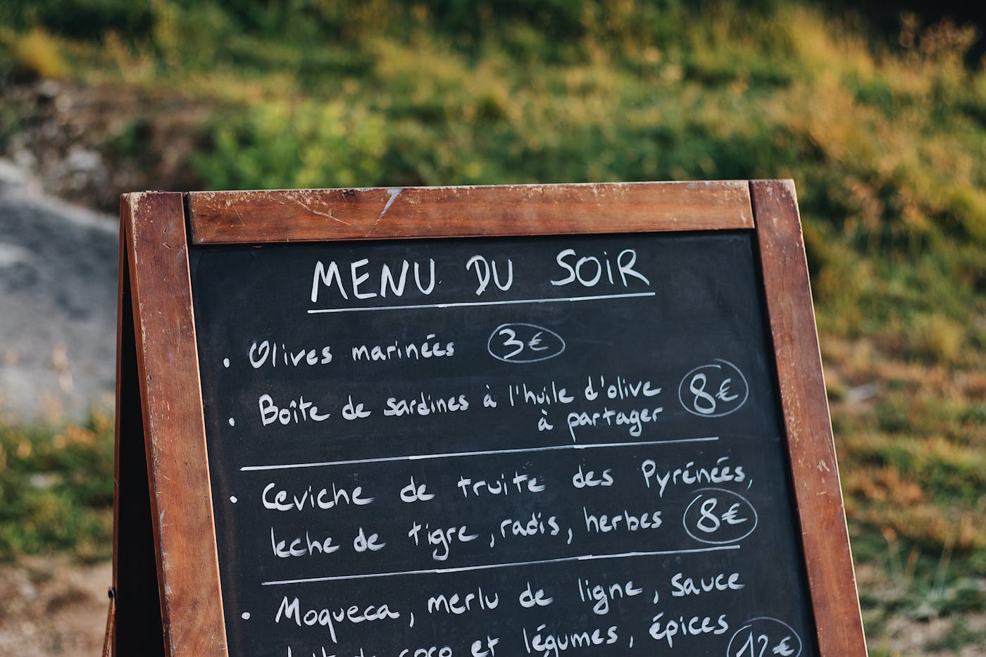 Lavagna menu esterna con voci di piatti francesi e prezzi