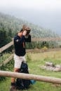 Hiker Standing Beside a Wooden Fence