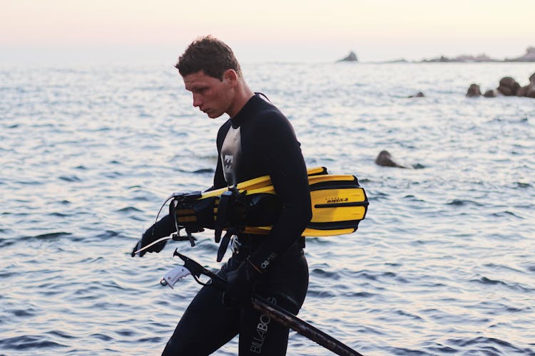 Man With Diving Gear Walking On Sea Shore