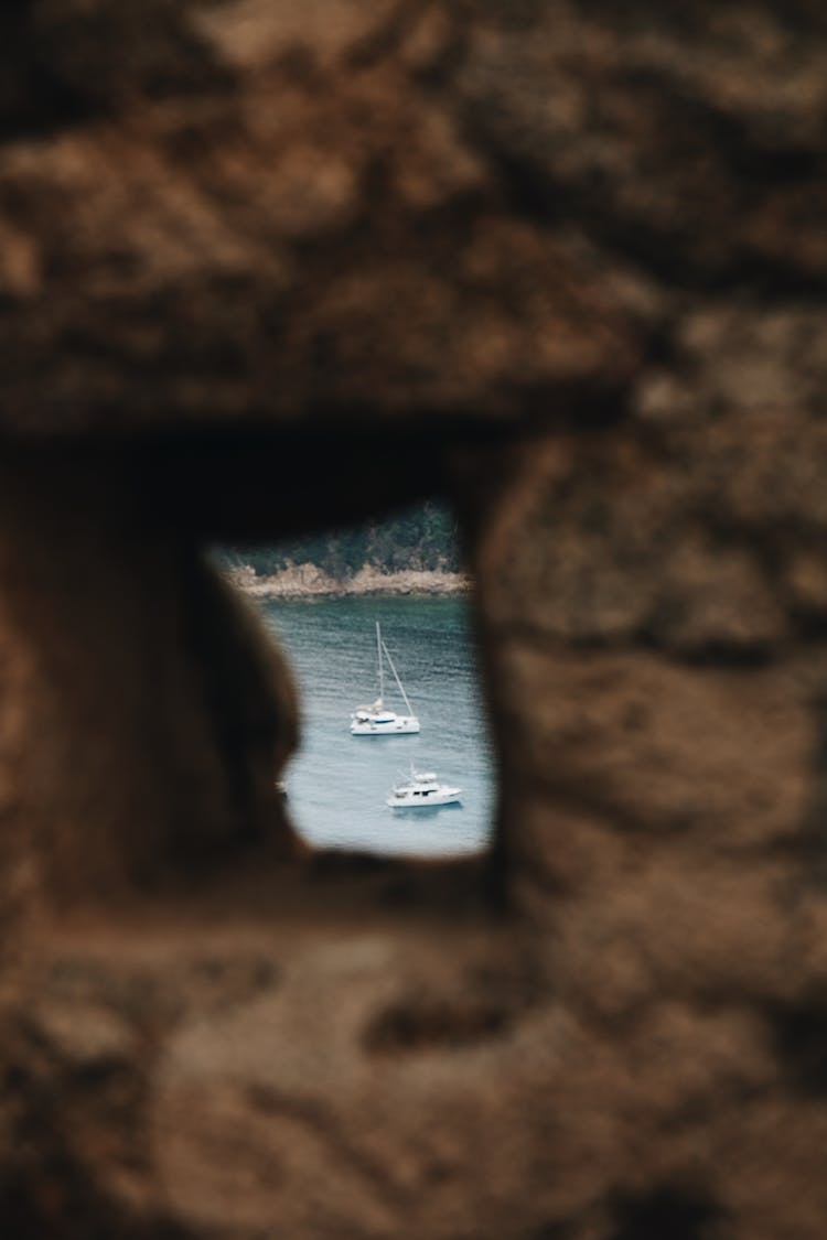 Hole In A Brown Stone Wall And Boats On A Lake