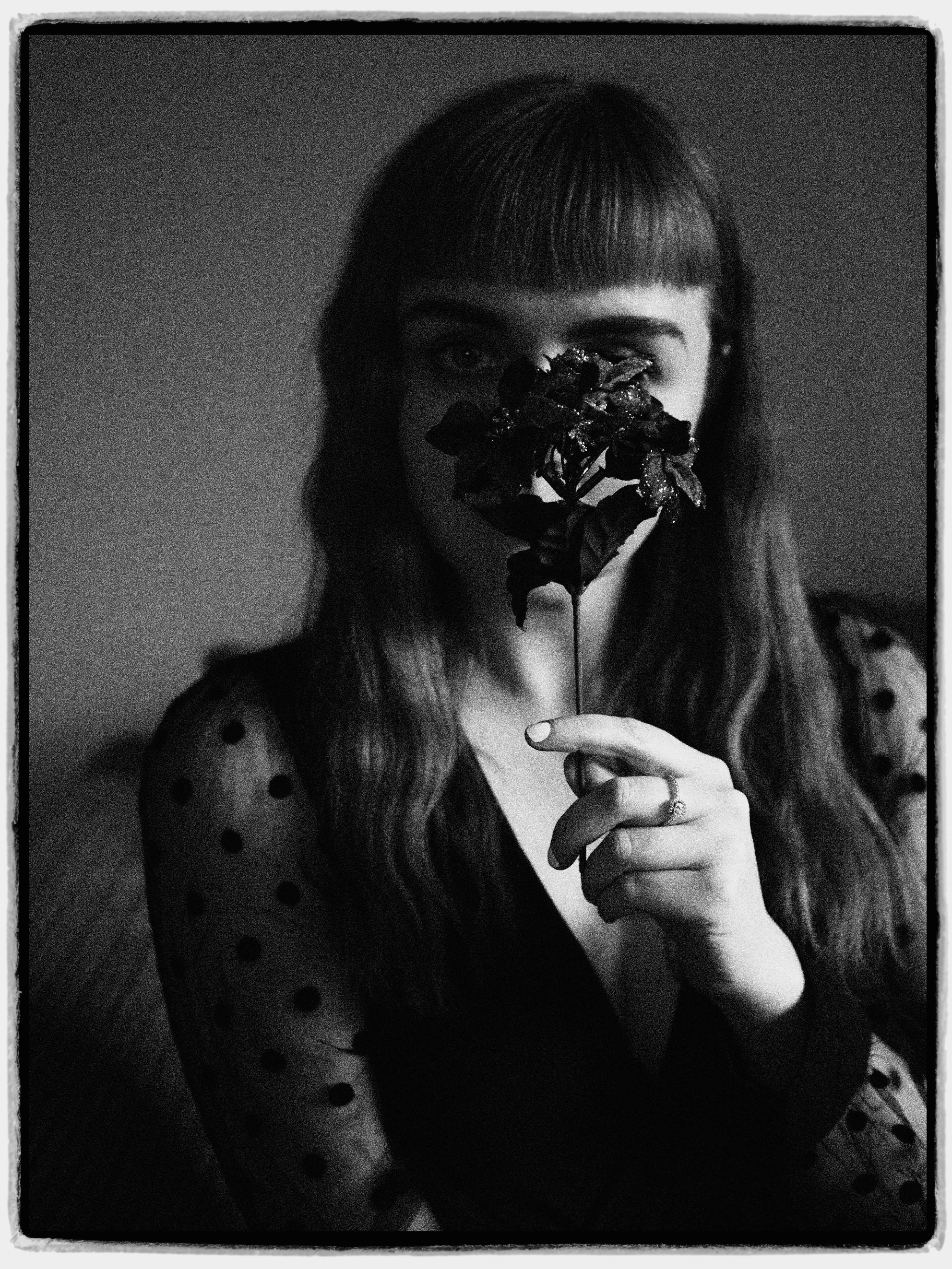 Black and white portrait of a well-dressed woman holding a flower.