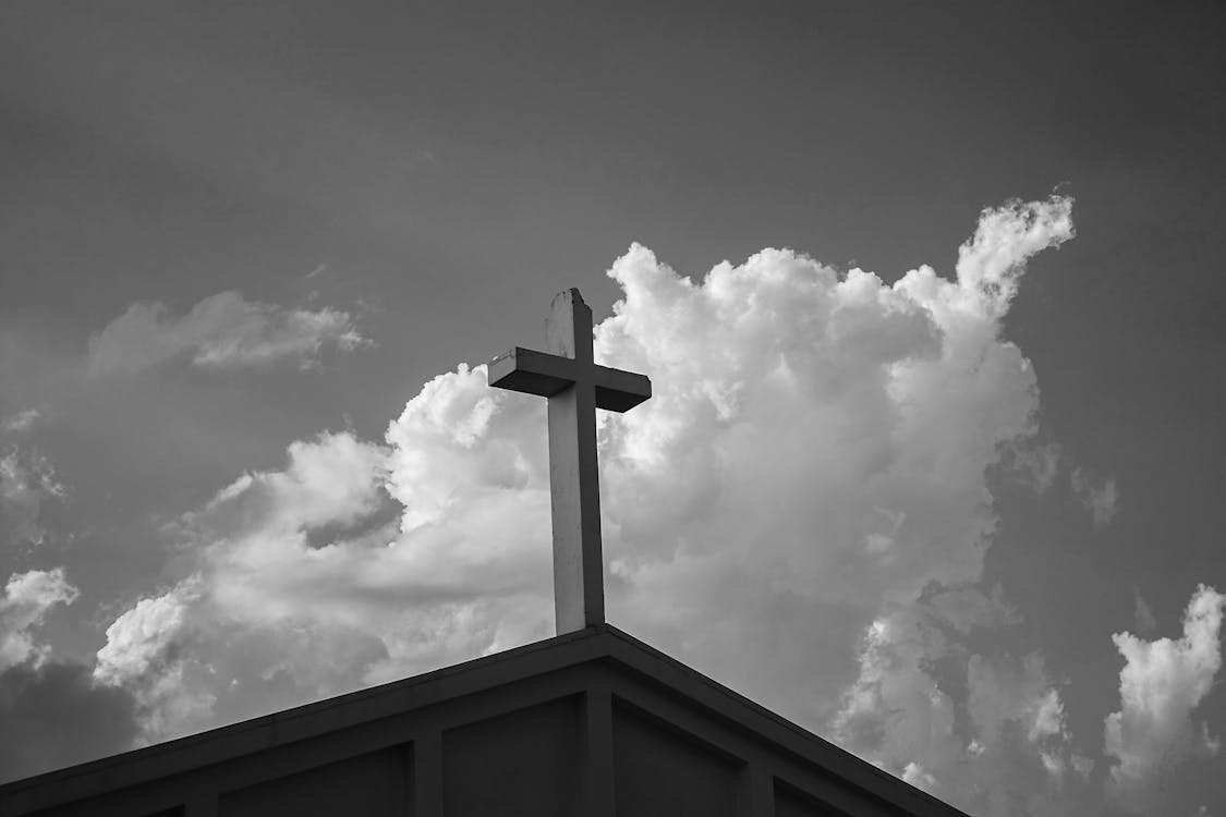 Free Grayscale Photo of Cross Under Cloudy Sky Stock Photo