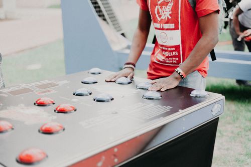 Free Group of young adults enjoying outdoor arcade buttons game in a park setting. Stock Photo