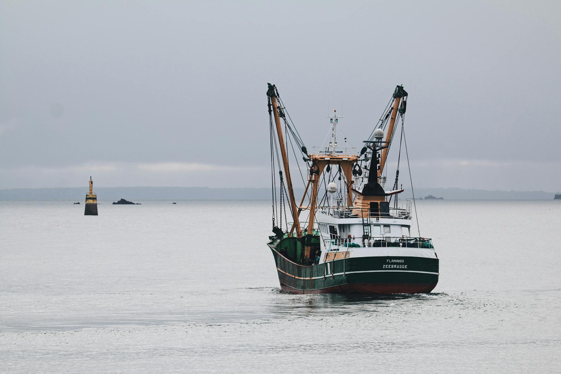 A fishing boat sails on calm seas near a buoy, showcasing maritime industry.