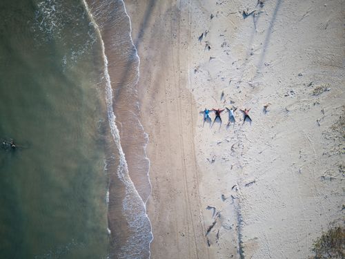 Free Drone captures serene scene of people lying on a sandy beach by the ocean. Stock Photo