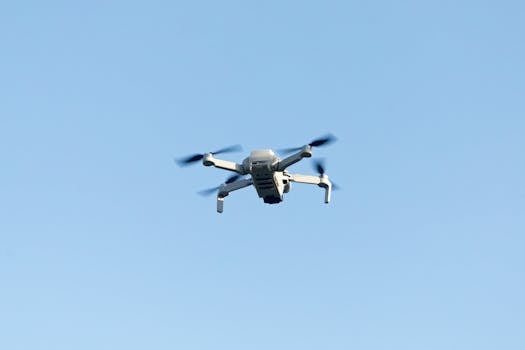 A sleek drone flying high against the clear blue sky, capturing stunning aerial footage.