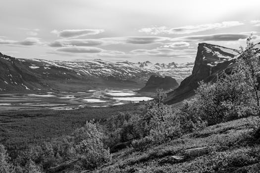 Monochrome view of a rugged valley and mountains under dramatic clouds, Sweden.