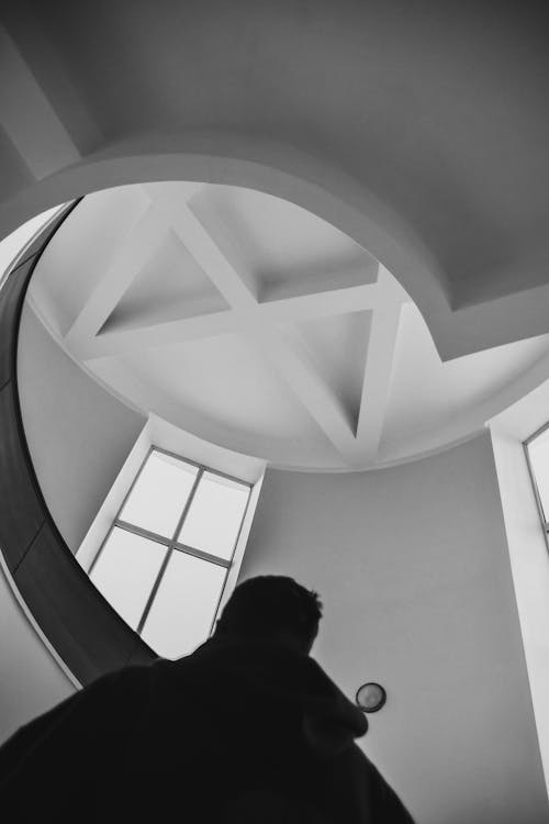 Silhouette of Man Standing near a Spiral Staircase